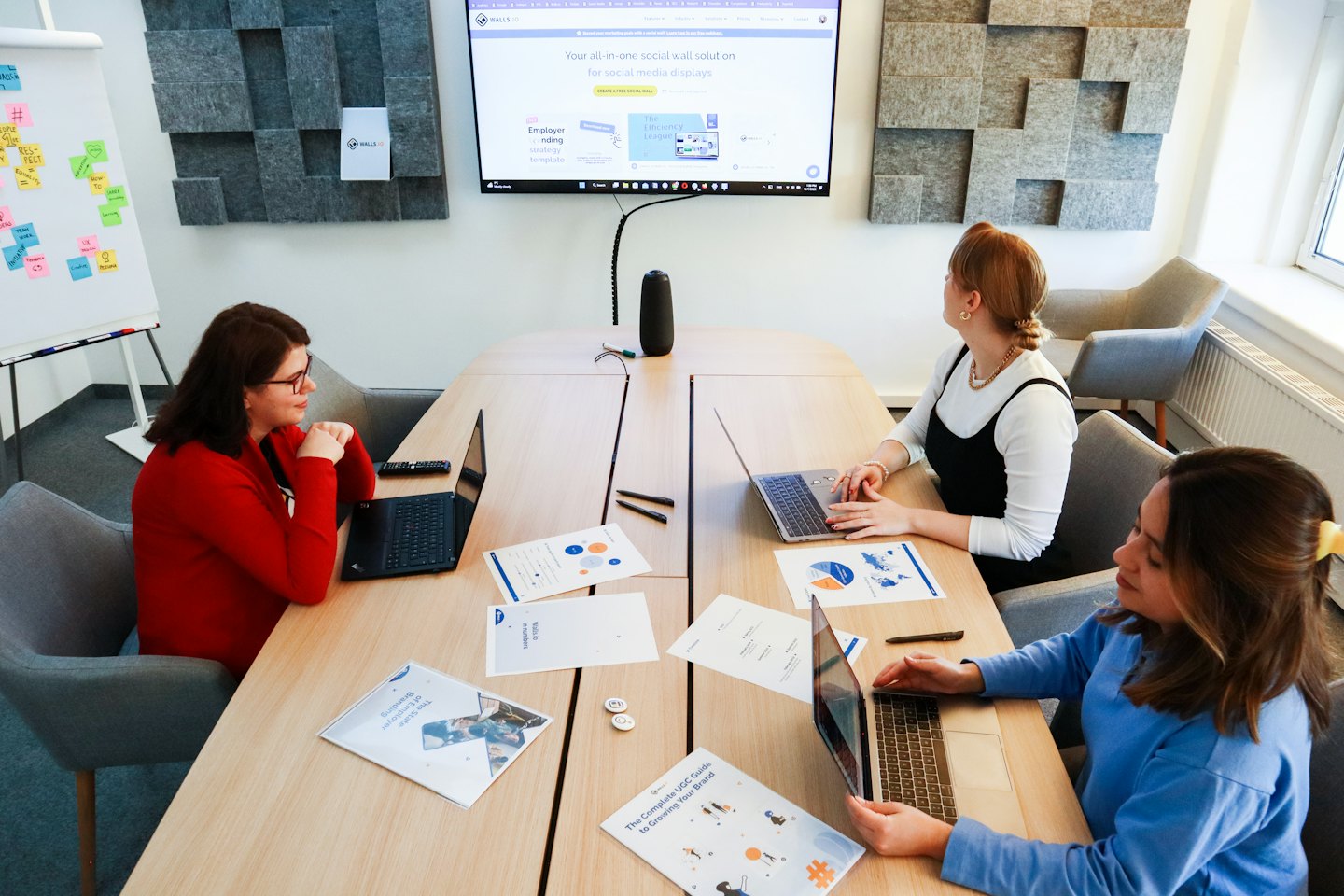 Drei Frauen arbeiten gemeinsam an Laptops an einem Bürotisch.