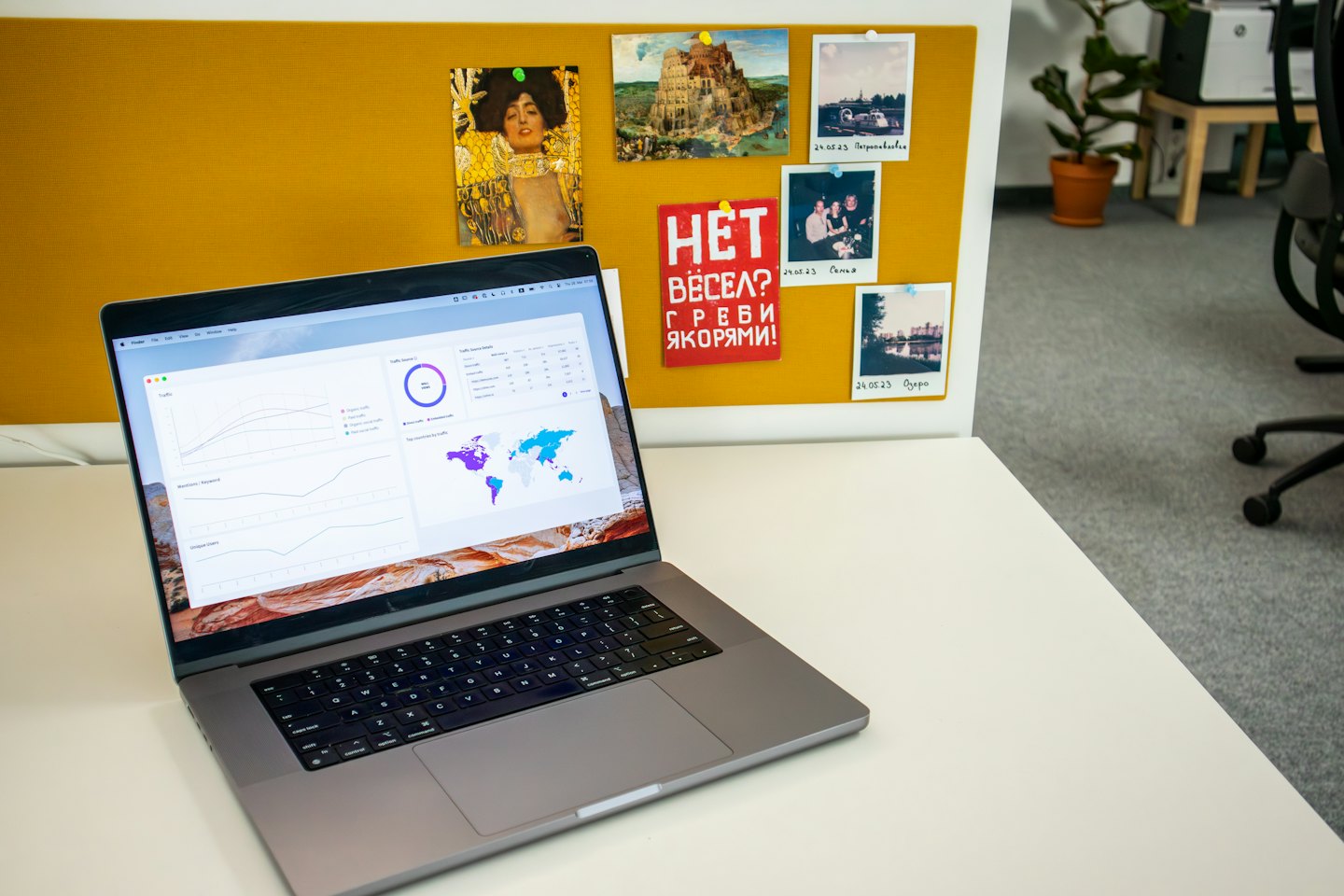 Silberner Laptop mit Datenanalyse-Dashboard auf einem weißen Schreibtisch.